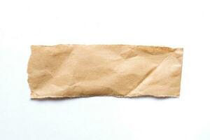 Close up of a ripped piece of brown paper on white background photo