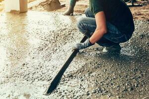 plasterer concrete worker at floor of house construction photo