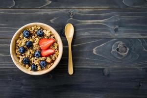 Homemade granola and fresh berries on wood table with space. photo