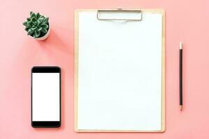 stationery, blank clipboard, smartphone, pot plant on pink pastel color with copyspace for background photo