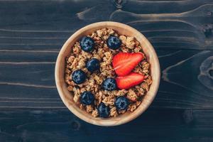 Homemade granola and fresh berries on wood table with space. photo