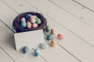 Easter egg and nest with blank paper on wood table background, copy space. photo