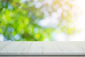 Empty wooden table and abstract blurred green bokeh leaves background texture, display montage with copy space. photo