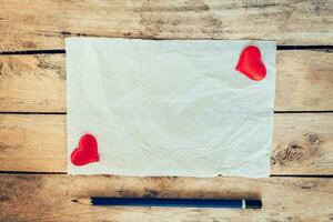 old paper and red heart with pencil on wood background for valentine greeting card. photo