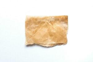 Close up of a ripped piece of brown paper on white background photo