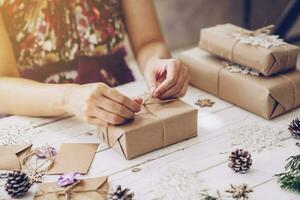 Woman hand making beautiful Christmas gift box at table photo