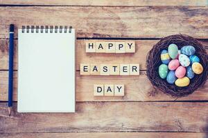 Blank notebook, Colorful easter egg in the nest and wood text for Happy Easter Day on wood background with space photo