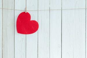 rojo corazón colgando en blanco madera antecedentes con Copiar espacio. foto