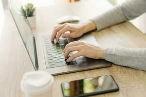 Business woman hand typing laptop computer on wooden table photo