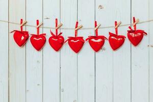 Red heart hanging at clothesline on wood white background with space. Valentine Day. photo