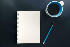 Office table with blank notepad, pencil, and cup of coffee. photo