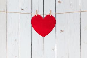 Red heart hanging at clothesline on wood white background with space. Valentine Day. photo