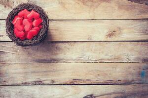 Red heart in the nest on wood background with space photo