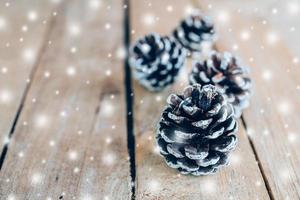 Pine cone and white snow on wood table background with space. photo