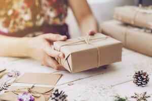 Woman hand holding beautiful Christmas gift box at table photo