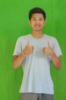 expressive casual Balinese Asian guy model for advertising with green screen studio background photo