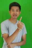 expressive casual Balinese Asian guy model for advertising with green screen studio background photo