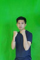 expressive casual Balinese Asian guy model for advertising with green screen studio background photo