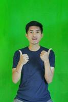 expressive casual Balinese Asian guy model for advertising with green screen studio background photo