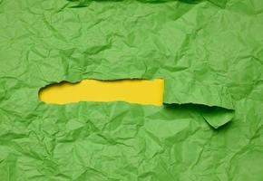 Texture of crumpled green paper with torn hole and yellow background, template for designer photo