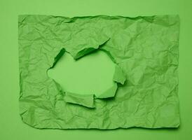 Texture of crumpled green paper with torn hole and green background, template for designer photo