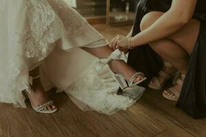 un dama de honor poniendo en el novias zapato foto