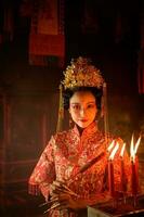 chino mujer hacer deseos, orar, y ligero velas en el ocasión de el anual chino nuevo año festival, en un venerado santuario o templo