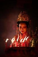 chino mujer hacer deseos, orar, y ligero velas en el ocasión de el anual chino nuevo año festival, en un venerado santuario o templo foto