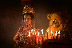 Chinese woman make wishes, pray, and light candles. On the occasion of the annual Chinese New Year festival, in a revered shrine or temple photo