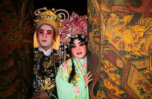 Portrait of male and female opera performers at the entrance to a sacred shrine or temple, praying for blessings on the occasion of the annual Chinese New Year. photo