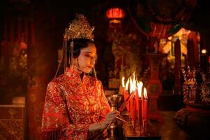 chino mujer hacer deseos, orar, y ligero velas en el ocasión de el anual chino nuevo año festival, en un venerado santuario o templo foto