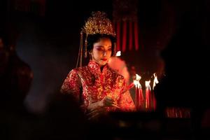 chino mujer hacer deseos, orar, y ligero velas en el ocasión de el anual chino nuevo año festival, en un venerado santuario o templo foto