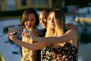 alegre multirracial mujer tomando selfie en muelle foto