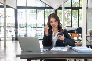 Asian businesswoman in black suit using a mobile phone to communicate with customers to report life insurance expenses and recording uncle's laptop inside office health insurance concept photo