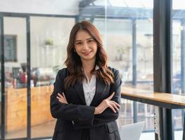 Marketing, Financial, Accounting, Planning, Smiling businesswoman standing with arms crossed happily leading a profitable business management team inside the office. photo