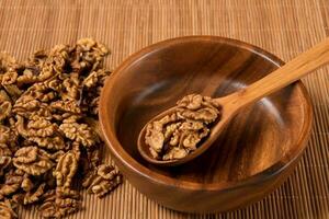 walnuts are put in a wooden bowl with a wooden spoon, culinary background photo