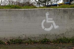 un silla de ruedas símbolo con estacionamiento espacio en un pared foto