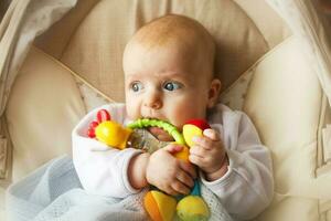 a small child lies and plays with a toy. baby with a toy in his mouth photo