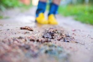 child in rubber boots walking outdoor. child's feet in a rubber boot photo