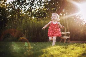 happy baby smiling. little girl running at sunset photo