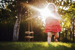 contento bebé sonriente. pequeño niña corriendo a puesta de sol foto