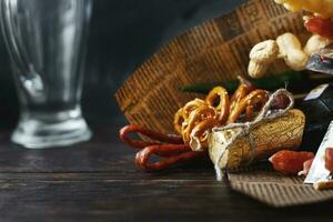 a can of beer with a snack on a wooden dark background with an empty beer glass. gift bouquet to a man photo