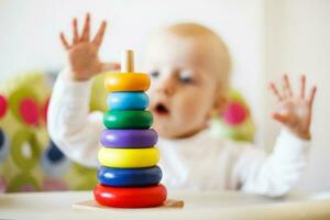 the kid plays the pyramid. child playing with wooden toys photo