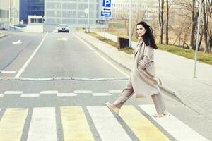 woman crossing the road at pedestrian crossing against urban city background photo