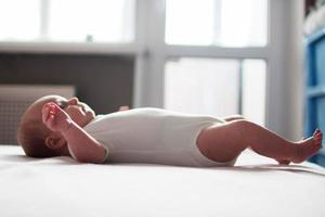 the infant lies on the bed in front of the window photo