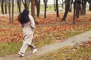 mujer en un gris Saco caminando en el otoño parque foto