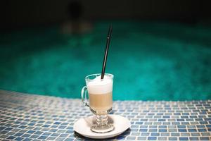 a cup of coffee in the pool and a girl in the background photo