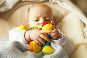 a small child lies and plays with a toy. A newborn baby in a deckchair with a toy in hand photo