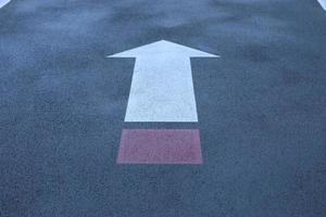 White and red direct arrow on asphalt street. Direction indicator. Signs on the street. photo