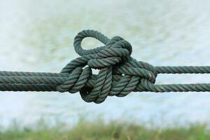 Twisted green cord on blurred water surface background. photo